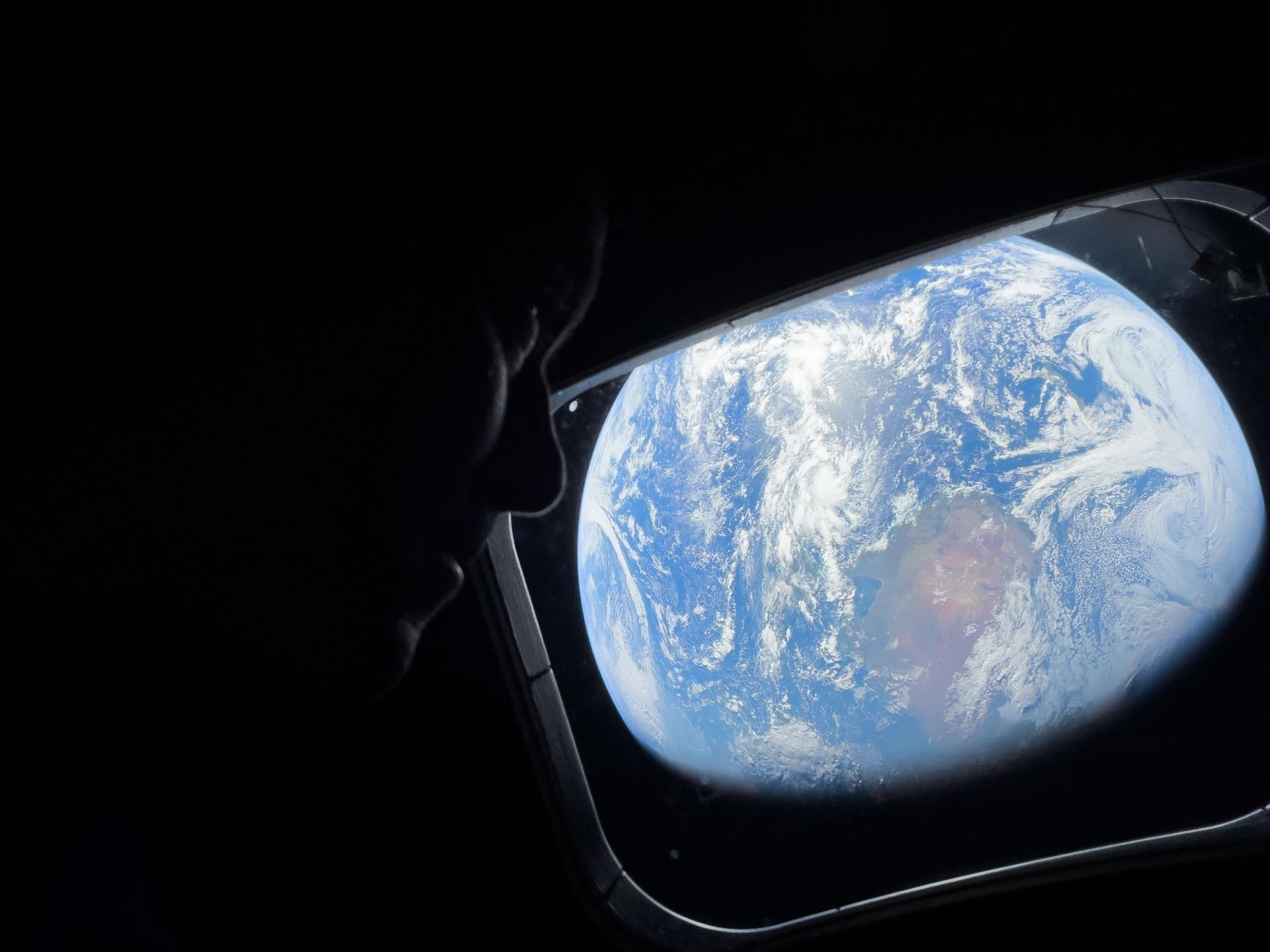 NASA astronaut and Artemis II Commander Reid Wiseman peers out of one of the Orion spacecraft's main cabin windows at Earth.  Image Credit: NASA