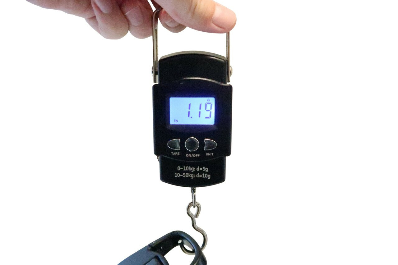 GSC International SD-50 in use weighing an object, demonstrating real-time digital measurement, illuminated LCD display, stainless steel hook, and practical application of force measurement principles.